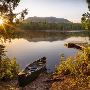 A canoe is pulled up on shore, perhaps to escape a swarm of black flies on a beautiful afternoon on Little Lyford Pond, just east of Moosehead.