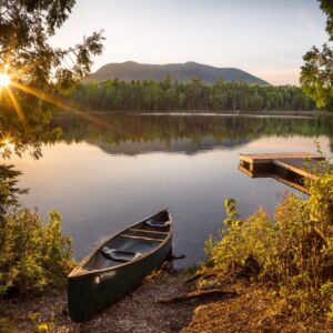 A canoe is pulled up on shore, perhaps to escape a swarm of black flies on a beautiful afternoon on Little Lyford Pond, just east of Moosehead.
